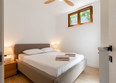 Bijela soba s bijeli plahtama na pruge, upaljene noćne lampe u našem šarmantnom apartmanu Lumbarda