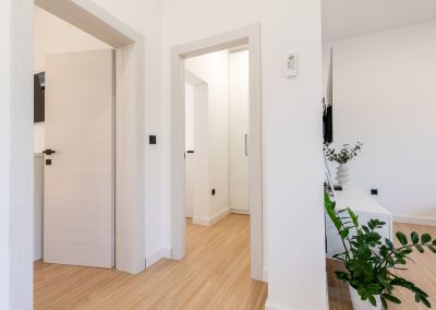 Hodnik s ulazom u 3 prostorije, biljka i plazma TV na zidu u našem šarmantnom apartmanu Lumbarda.