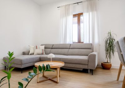 Veliki trosjed s bijelim zidovima i prozorom s bijelim zavjesama u šarmantnom apartmanu Lumbarda