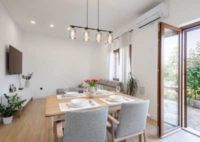 Stol posložen za četvero, dnevni boravak i otvorena vrata na terasu našeg šarmantnog apartmana Lumbarda