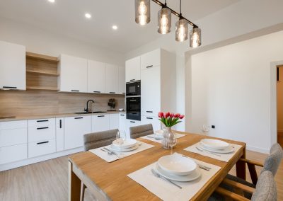 Pogled na bijelu kuhinju i posložen stol za četvero u šarmantnom apartmanu Lumbarda